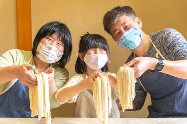 A family holding the fresh noodles they made at the morning noodle-making experience